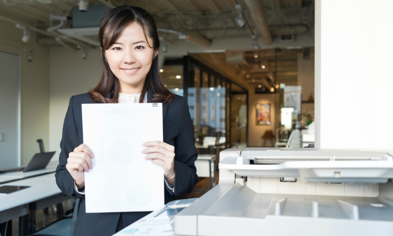 書類を両手に持つ若い女性