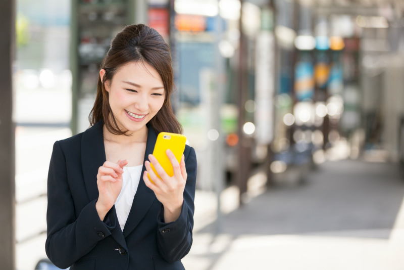 スマホを見る笑顔のスーツ姿の女性