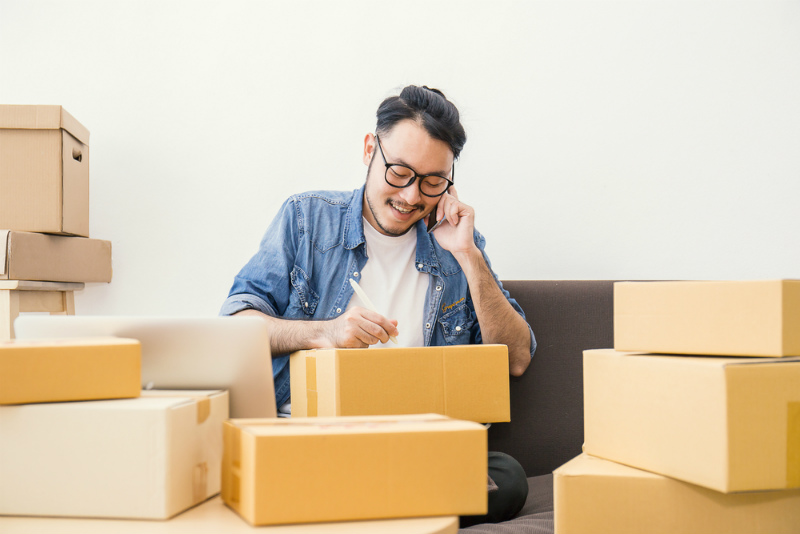 段ボールで荷物をまとめる男性