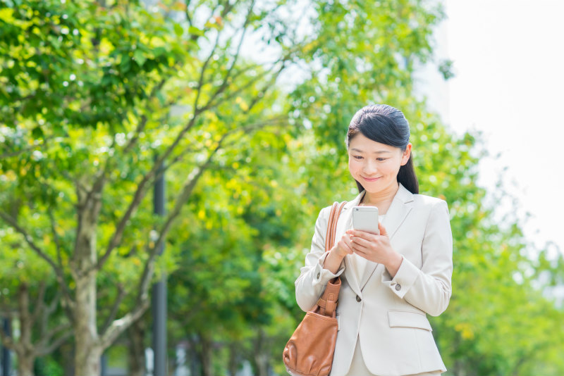 笑顔でスマートフォンを操作する女性