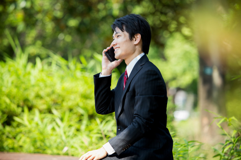 屋外で電話しているスーツ姿の若い男性