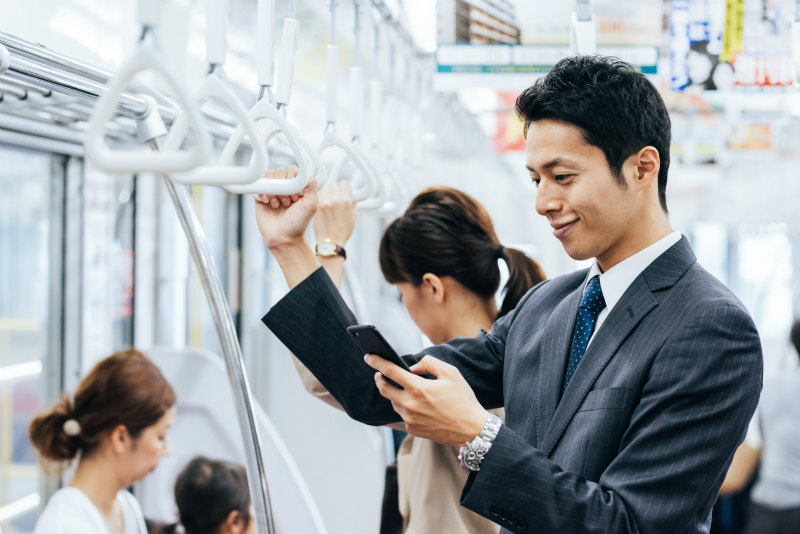 通勤電車でスマホを見ている男性