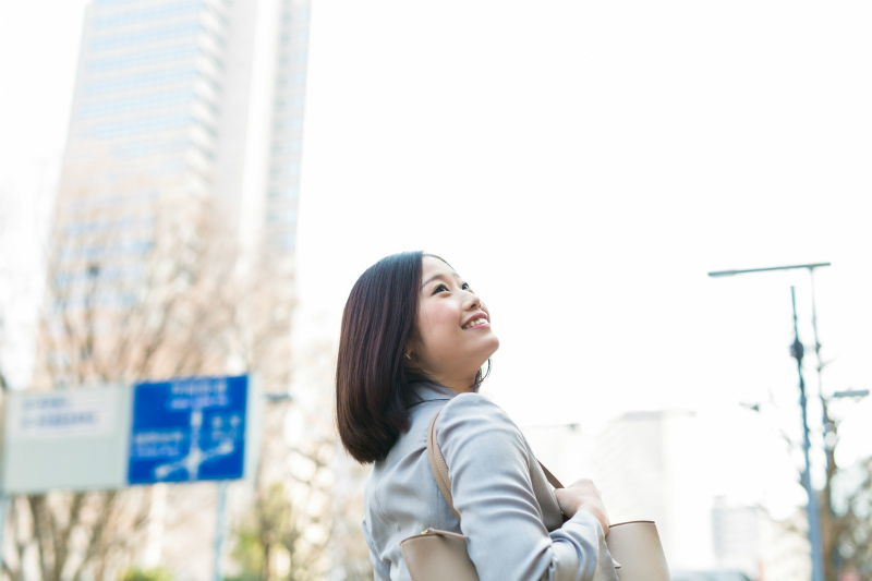 オフィスカジュアルの女性が屋外を歩いている様子