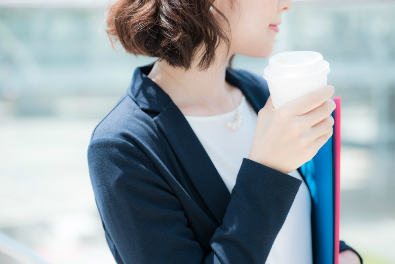 コーヒーを片手に何かを見つめる女性