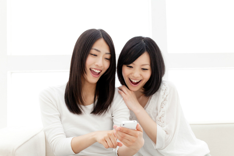 スマホを見て話す2人の女性